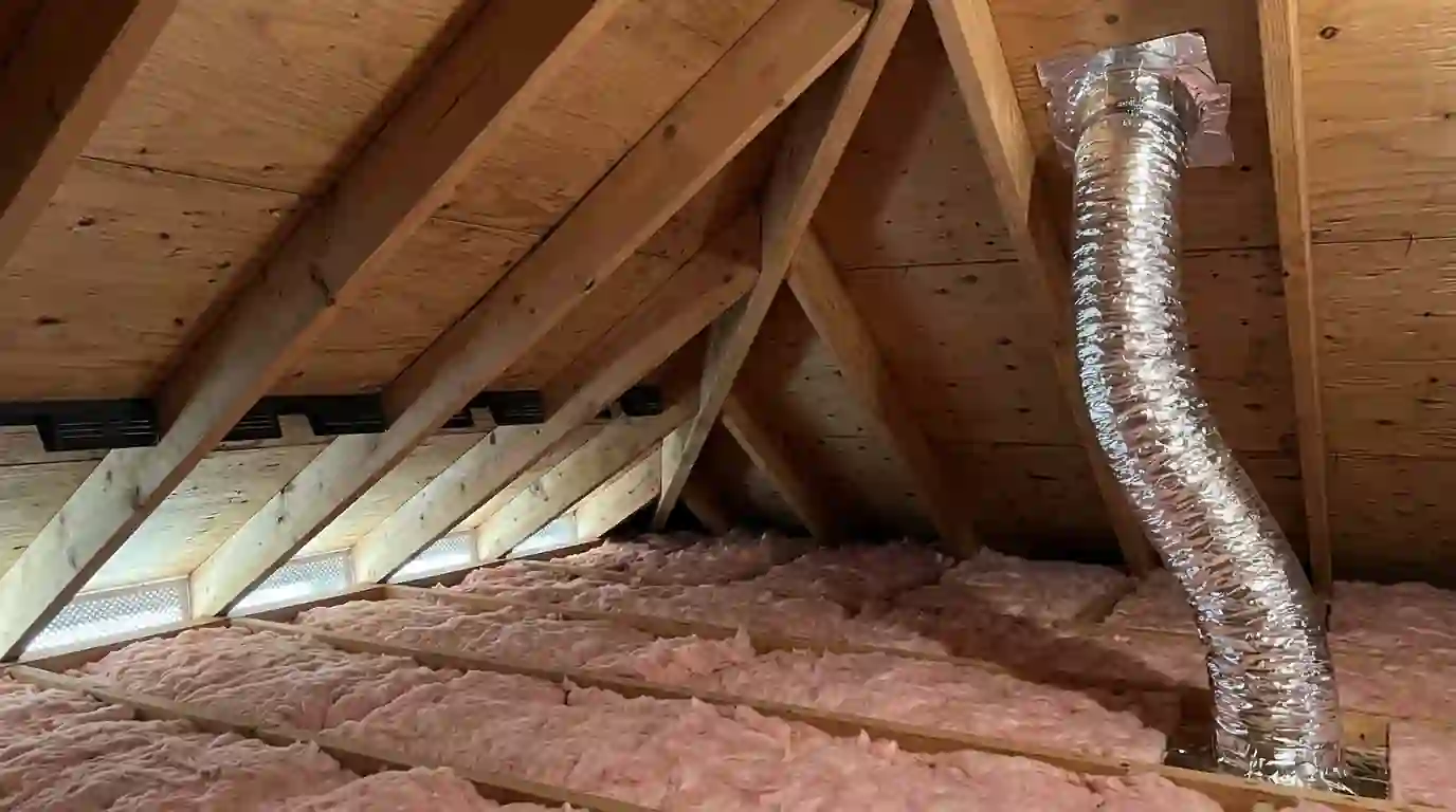 Bath fan duct routed to a roof cap in the attic
